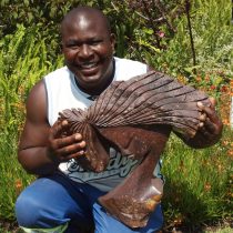 Zimbabwean artist Lovemore Bonjisi with one of his sculptures